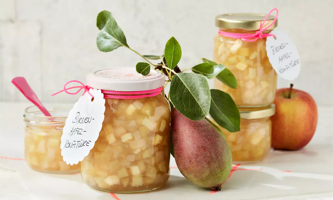 Carrés translucides de poires et pommes dans un sirop doré, en pots de verre décorés de rubans roses et feuilles fraîches