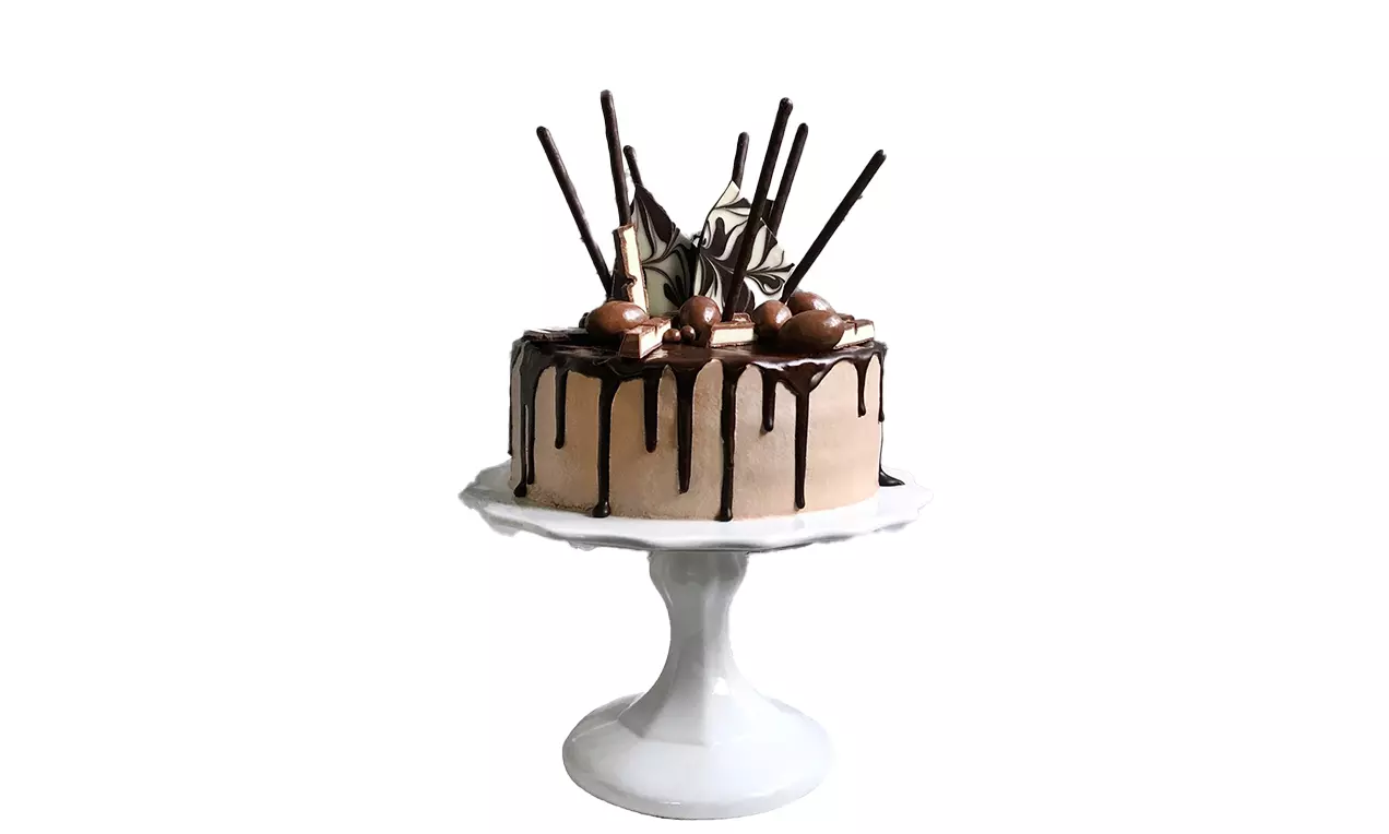 Drip Cake mit cremefarbener Glasur und dunklen Schokoguss-Streifen, dekoriert mit Pralinen, Schokostäbchen und Schokoladenscheiben auf weißer Tortenplatte