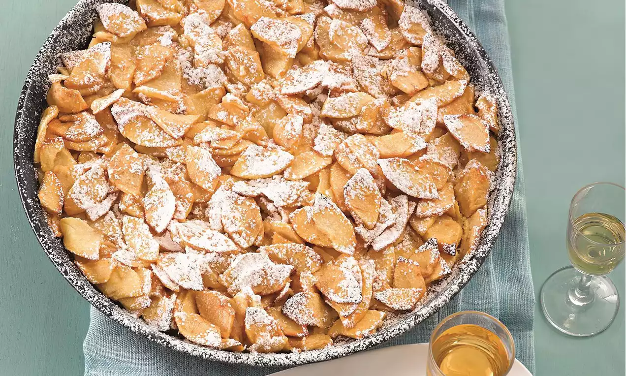 Sottili sfoglie dorate ripiegate e cosparse di zucchero a velo, disposte in modo uniforme su un piatto rotondo decorato