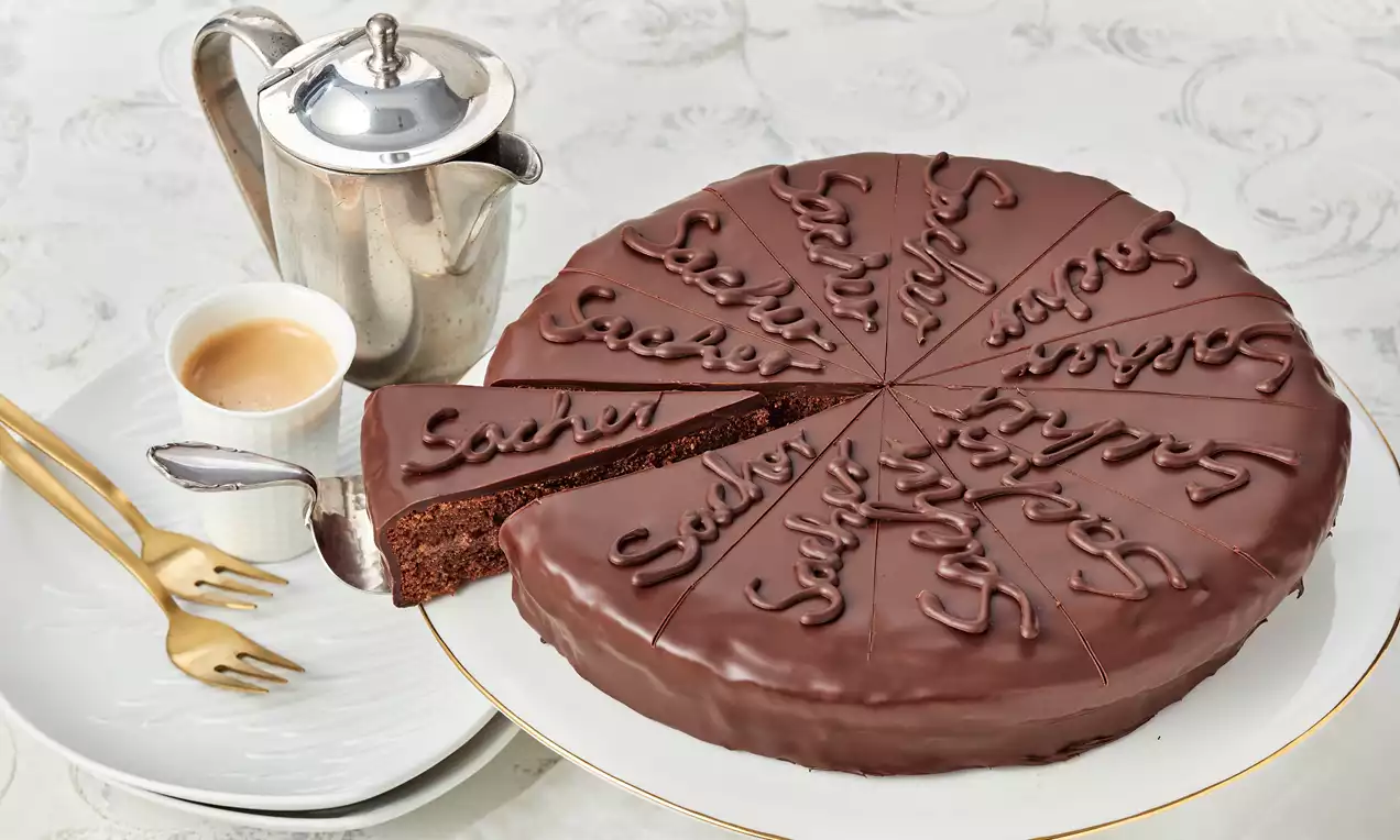 Sachertorte auf weissem Tisch mit einem Kaffee als Dekoration