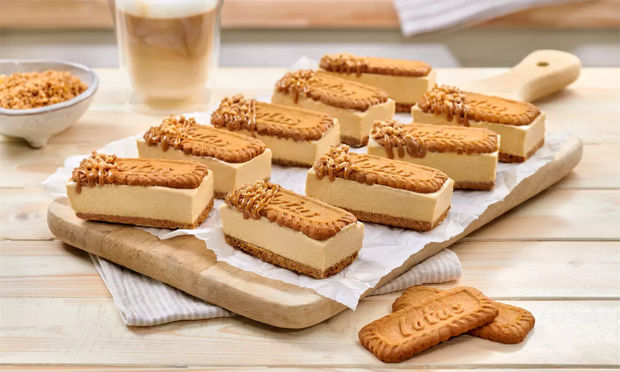 Rechteckige Lotus-Eis-Sandwiches mit karamellfarbener Biskuitober- und Unterseite, dekoriert mit Karamellcreme und Krokant auf Backpapier